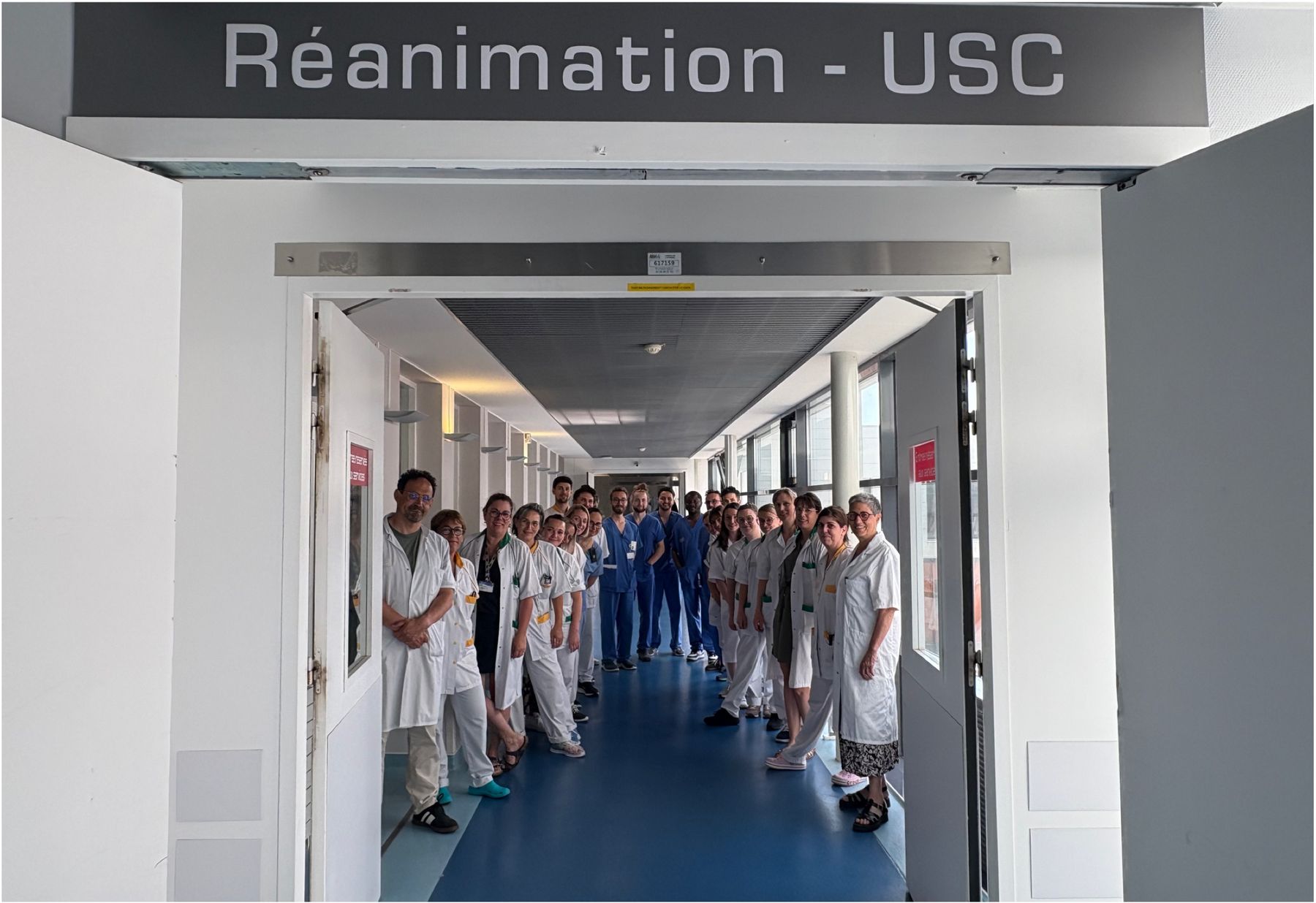 L'équipe du service réunie dans le couloir, sous le panneau Réanimation – USC.