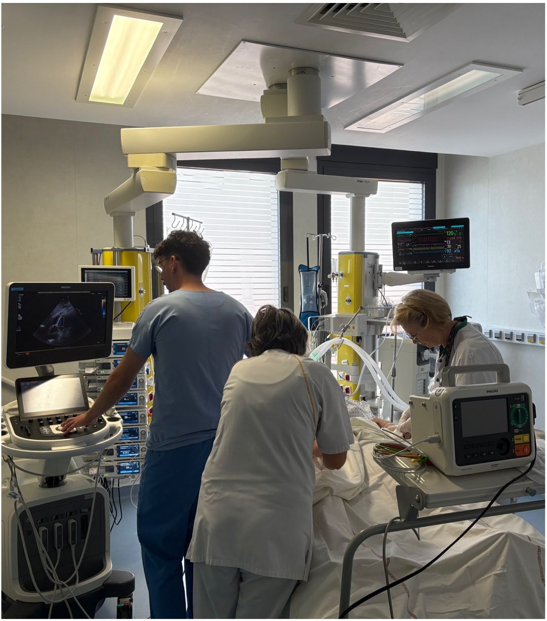 Une chambre de réanimation, avec l'équipe soignante au chevet du patient et les appareils de surveillance.