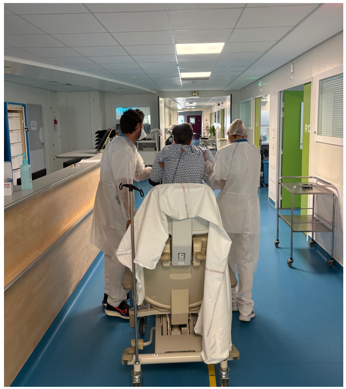 Deux kinésithérapeutes du service accompagnent la marche d'un patient dans le couloir de la réanimation.